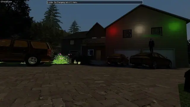 A house at night lit with red, white and green lights, with cars in the driveway